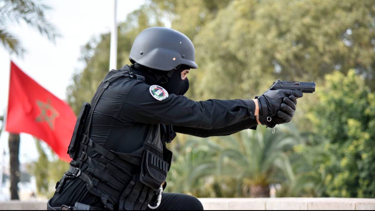 شرطي مغربي يشهر مسدسه
