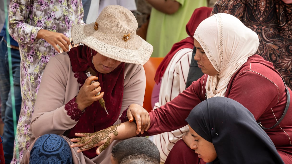 Une femme tatoue la main d'une autre femme au henné lors du festival annuel du Moussem à El Jadida, le 6 août 2023