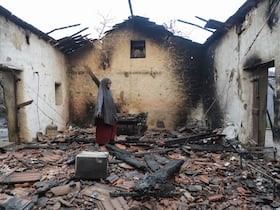 Une femme inspecte sa maison endommagée après qu'elle a été ravagée par un feu de forêt à Bordj T'har, une commune de la province de Jijel, dans le nord-est de l'Algérie, le 27 août 2026.