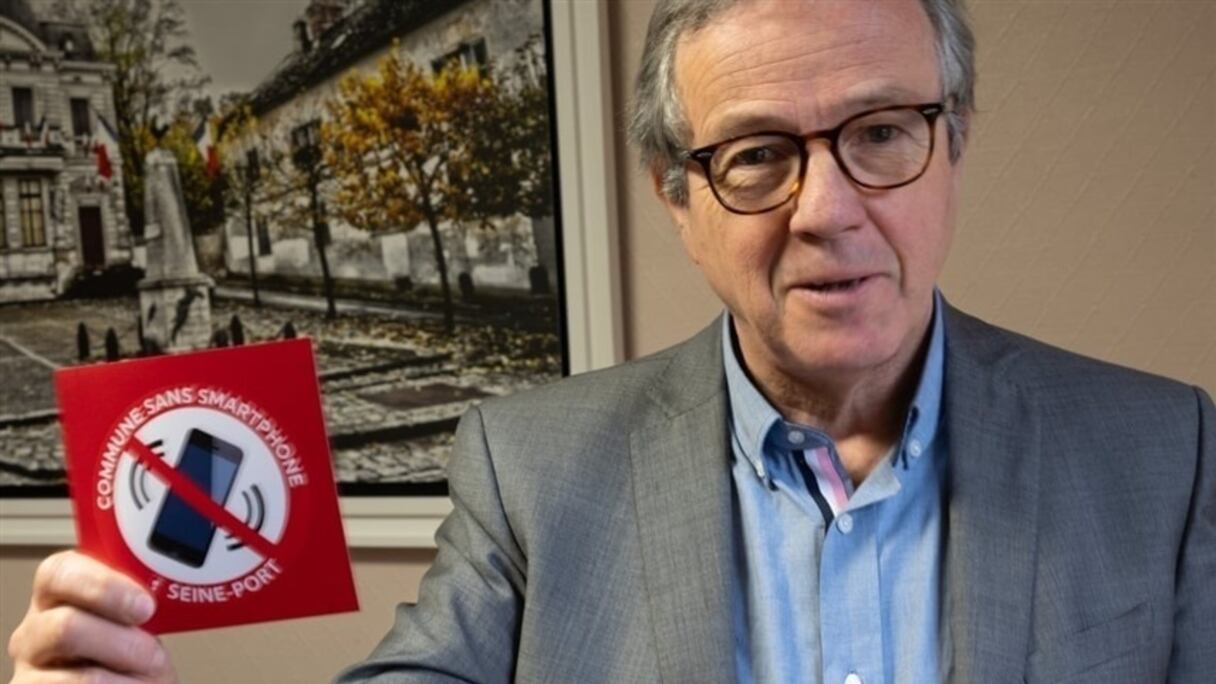 رئيس البلدية حاملاً الملصق التحذيري من استخدام الهواتف