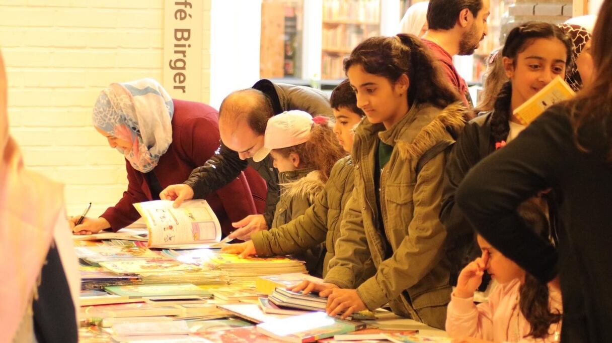 أطفال يتفحصون مع ذويهم كتبا في معرض للكتاب
