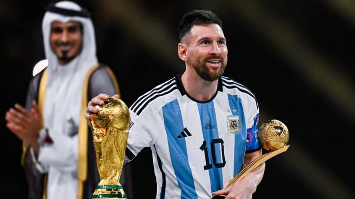 اللاعب الأرجنتيني ليونيل ميسي إلى جانب مجسم كأس العالم في قطر 2022
